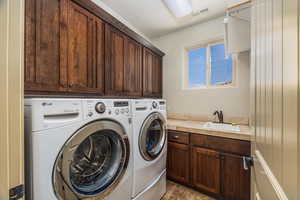 Laundry area featuring washing machine and clothes dryer, cabinet space, and light tile patterned flooring