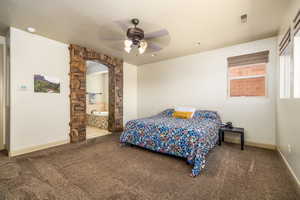 Master Suite with carpeted bedroom featuring ceiling fan, ensuite bathroom, and arched walkways