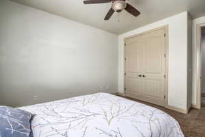 Carpeted bedroom with a closet and a ceiling fan