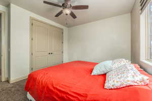 Carpeted bedroom with multiple windows, ceiling fan, and a closet