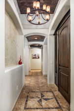 Hallway with arched walkways, inlaid floor details, and a chandelier