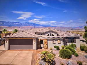 Mediterranean / spanish-style house with an attached garage, stucco siding, driveway, and a mountain view