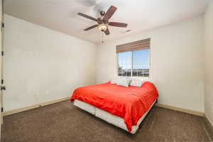 Carpeted bedroom with a ceiling fan and baseboards