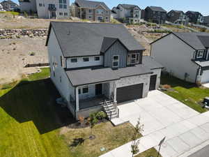 View of front of house with board and batten siding, covered porch, roof with shingles, a garage, and a front yard
