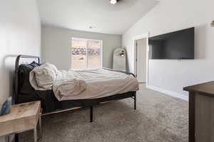 Carpeted bedroom featuring baseboards and vaulted ceiling