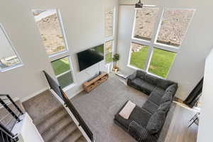 Carpeted living area featuring a towering ceiling, healthy amount of natural light, and ceiling fan