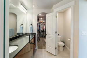 Bathroom with light tile patterned floors, double vanity, and a walk in closet