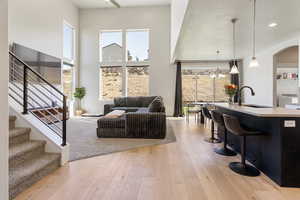 Living area with light wood-style flooring, a chandelier, stairway, washer / clothes dryer, and arched walkways