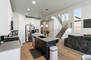 Kitchen with decorative light fixtures, white cabinetry, appliances with stainless steel finishes, recessed lighting, and light wood-type flooring