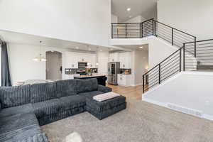 Living room with a towering ceiling, a chandelier, recessed lighting, arched walkways, and light wood-style floors