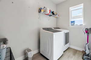 Washroom with light wood-type flooring and washer and clothes dryer
