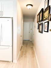 Hallway with baseboards and light laminate flooring
