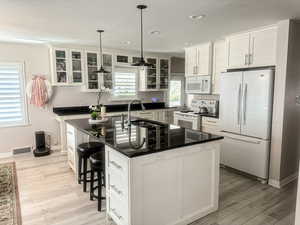 UPDATED Kitchen with updated  white cabinets, white appliances, recessed lighting, large granite island and new laminate flooring!