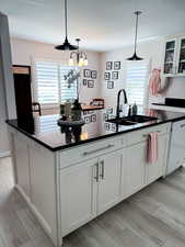 Kitchen with a kitchen island with sink, light wood-style floors, and hanging light fixtures