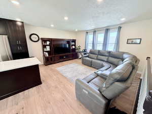 Living area with a textured ceiling, recessed lighting, and light wood-type flooring