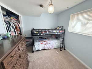Bedroom with light colored carpet, a closet, and a textured ceiling