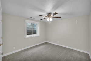 Carpeted empty room with a textured ceiling and a ceiling fan
