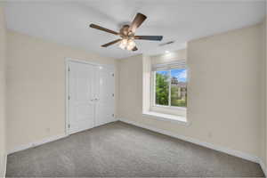 Unfurnished bedroom featuring carpet floors, a closet, and a ceiling fan