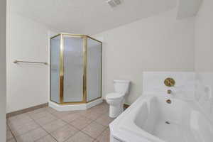 Bathroom featuring a bath, light tile patterned flooring, a shower stall, and a textured ceiling