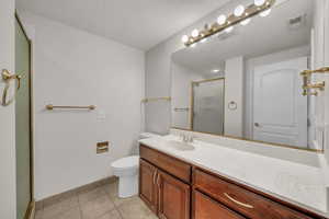 Full bathroom featuring vanity, a stall shower, light tile patterned flooring, and a textured ceiling
