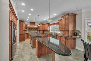 Kitchen featuring a center island with sink, brown cabinets, dark stone counters, glass insert cabinets, and recessed lighting