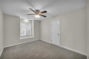 Spare room with carpet floors, a ceiling fan, and a textured ceiling