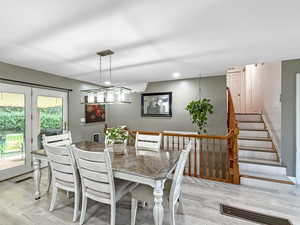 Dining area with wood finished floors, stairs, and recessed lighting