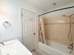 Bathroom with shower / tub combo with curtain, light wood-style floors, and vanity