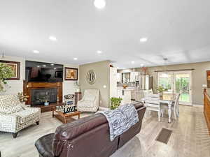 Living area with light wood-style floors, a glass covered fireplace, and recessed lighting