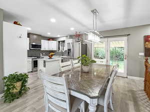 Dining room with light wood finished floors and recessed lighting