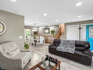 Living room with wood finished floors, recessed lighting, and stairway