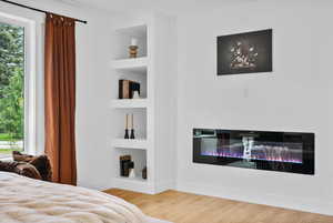 Master suite featuring wood finished floors and a glass covered fireplace