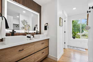 Master bath with double vanity, light wood finished floors, and recessed lighting