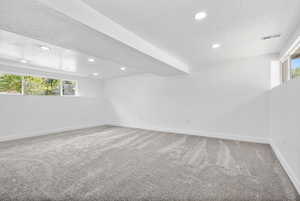 Unfurnished room with a textured ceiling, light colored carpet, and recessed lighting