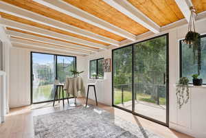 Sunroom / solarium featuring beam ceiling, wood finished floors, and wooden walls