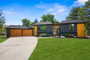 View of front facade with a front yard, a chimney, and driveway