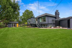 Rear view of property featuring stairway, an outbuilding, a chimney, a yard, and brick siding