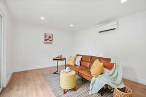 Living area featuring recessed lighting, light wood-style flooring, and a wall mounted air conditioner