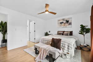 Master suite featuring light wood-style floors and a ceiling fan