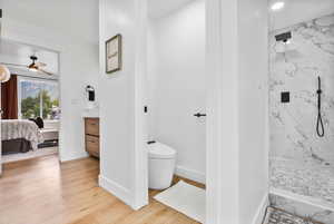 Master bath with a marble finish shower, connected bathroom, light wood-style flooring, a ceiling fan, and vanity
