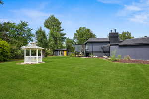 View of grassy yard featuring a gazebo and an outbuilding