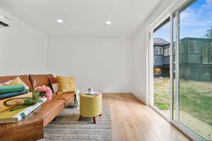 Living area featuring recessed lighting, light wood-type flooring, and a wall mounted air conditioner