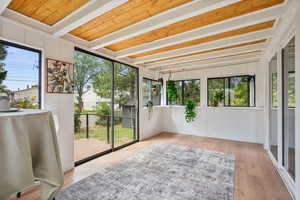 Unfurnished sunroom with beam ceiling and wood finished floors