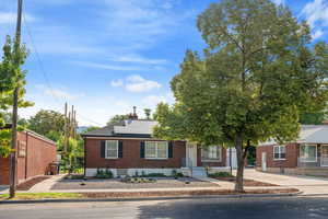 Street view of front of property featuring basement entry, front entry, xeriscaped yard, solar panels, brick siding, and a chimney