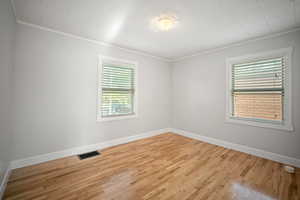 Second bedroom with light wood-style floors and ornamental molding