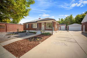 View of front of property with xeriscaped yard, brick siding, roof mounted solar panels, and a detached garage