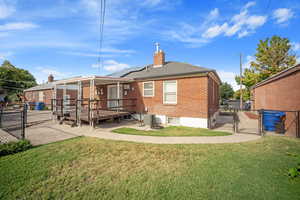 Rear view of house with a gate, solar panels, brick siding, a chimney, and a deck