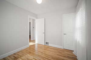 Third bedroom with light wood-style floors, ornamental molding, and closet