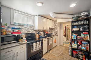 Kitchen featuring white cabinetry, dishwasher with stainless steel finish, and backsplash