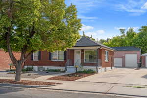 View of front of home featuring concrete driveway, brick siding, a porch, a garage, and a shingled roof